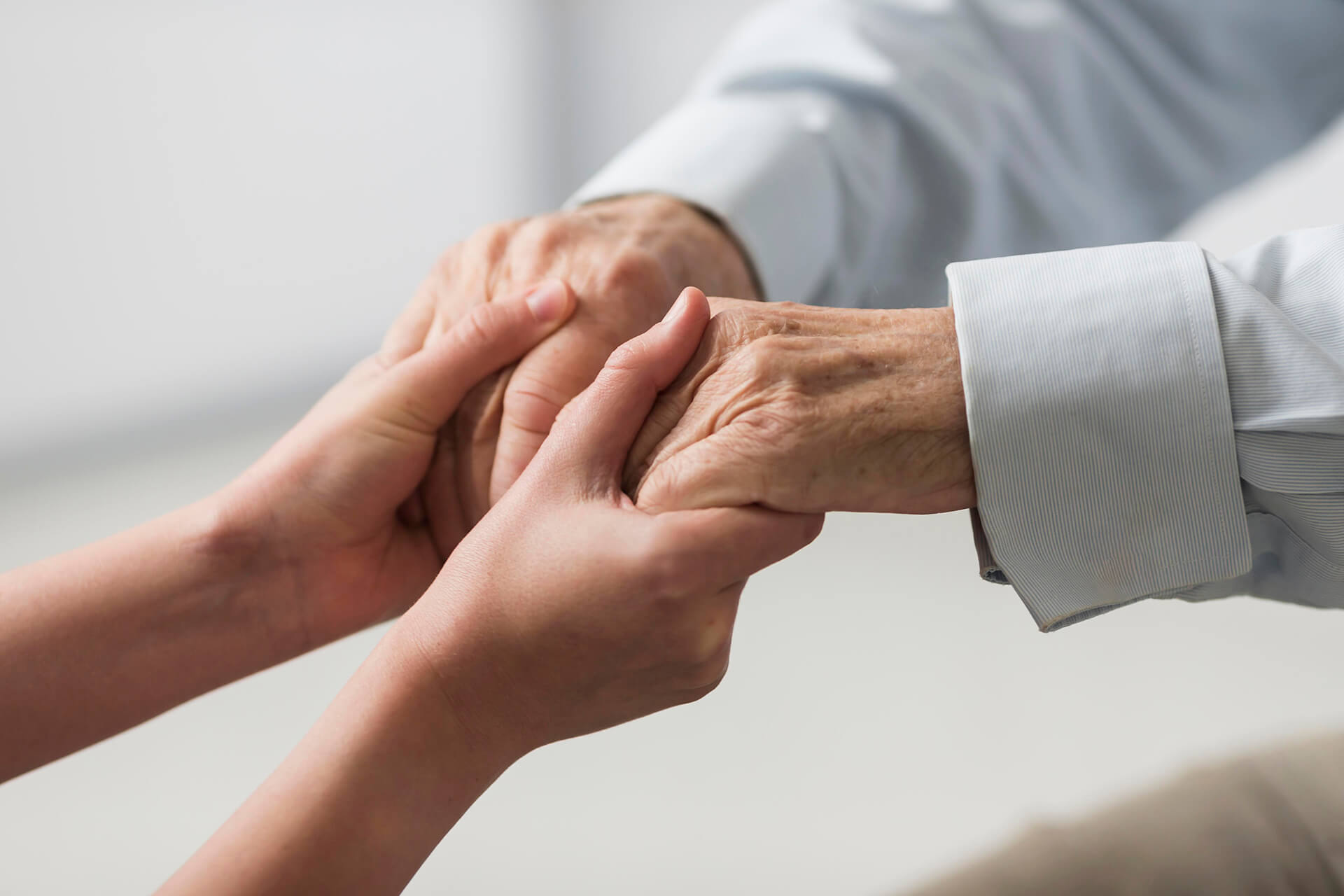 Close-up of a caregiver holding hands with an elderly person, symbolizing compassion, trust, and dedicated senior home care services.