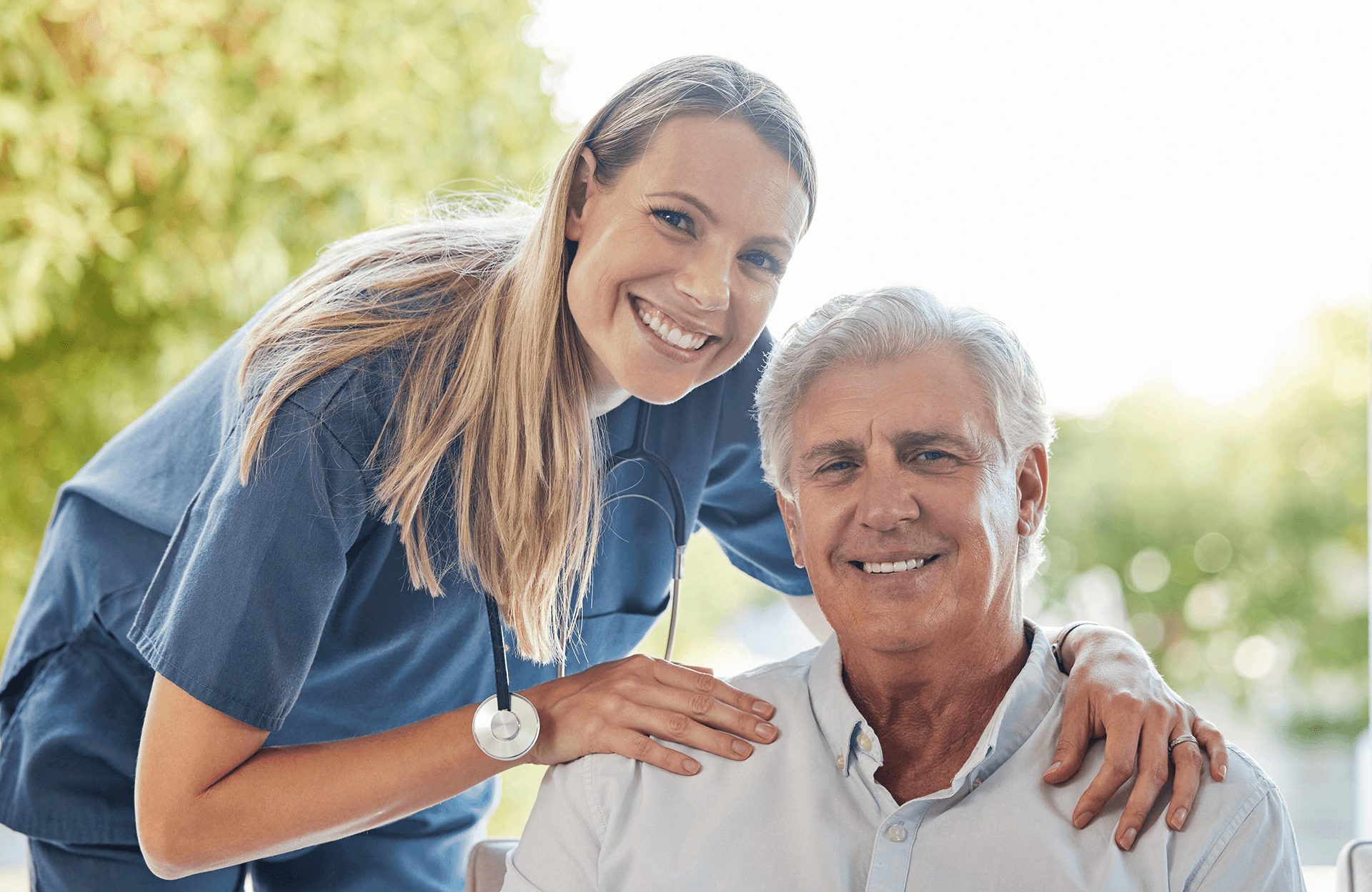 Smiling female caregiver with stethoscope supporting a happy senior man, showcasing professional and compassionate in-home care by Sunshine Home Care Services.