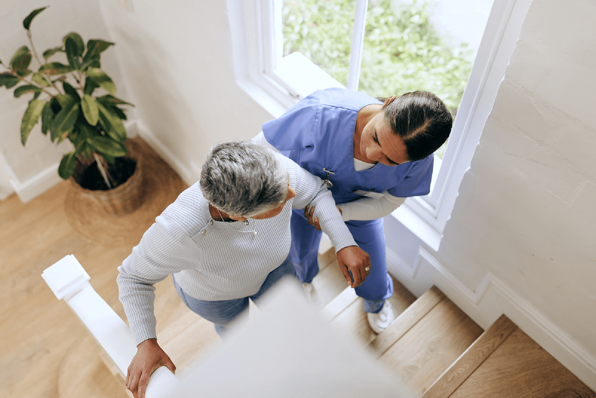 Caregiver assisting an elderly woman safely up the stairs, representing Sunshine Home Care Services’ focus on mobility support and fall prevention.