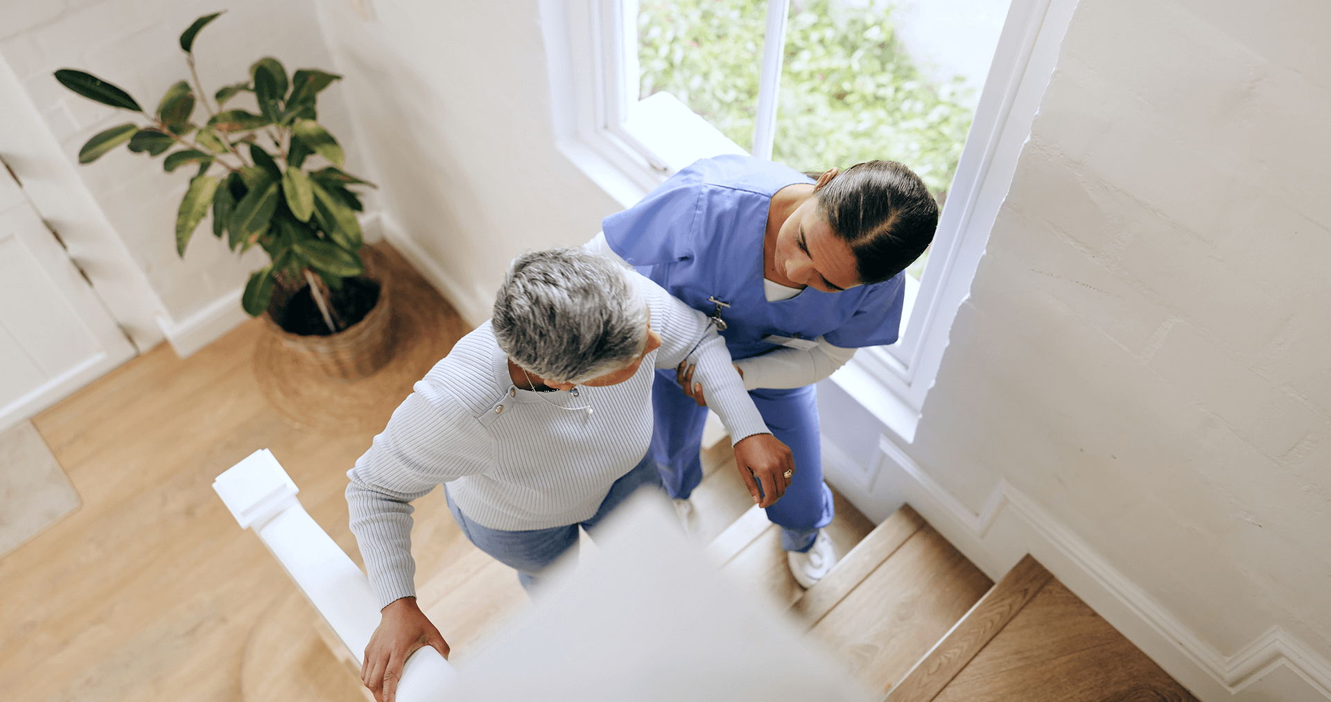 Caregiver assisting an elderly woman safely up the stairs, representing Sunshine Home Care Services’ focus on mobility support and fall prevention.