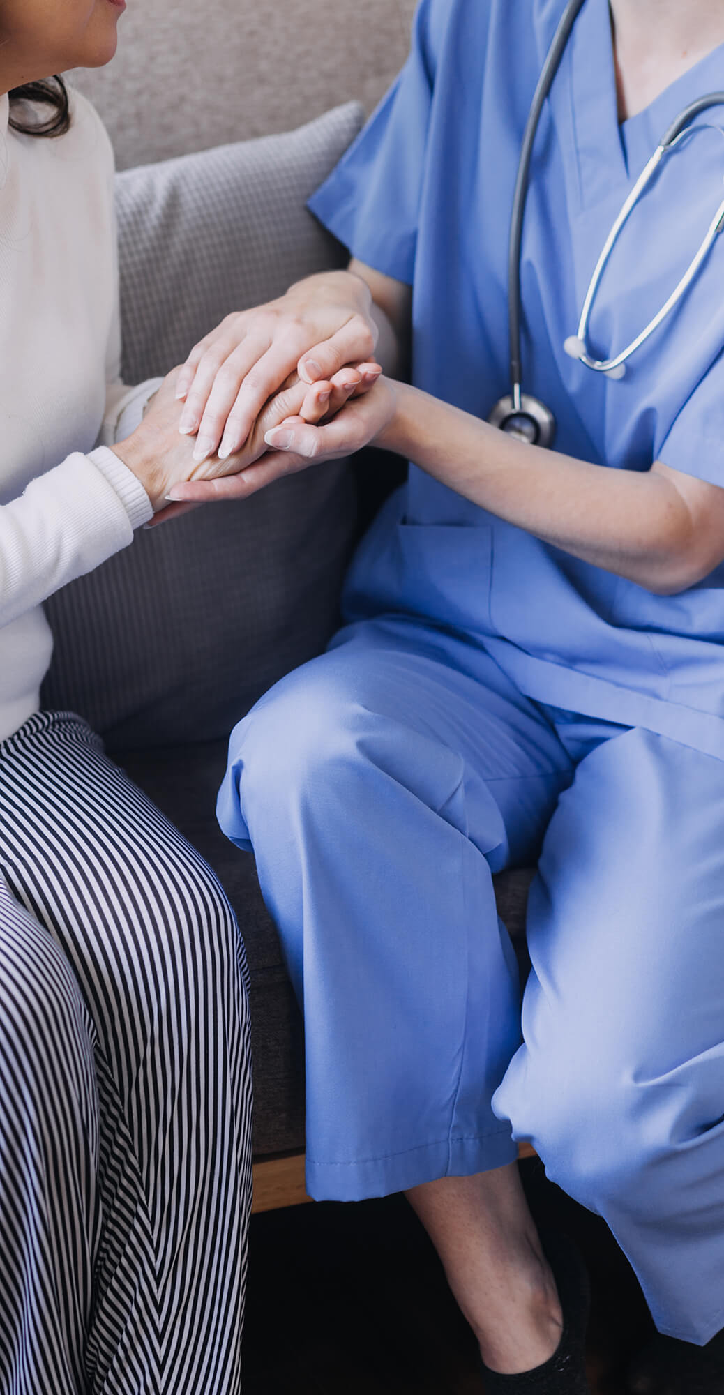 Close-up of a nurse in blue scrubs holding hands with a senior patient, symbolizing trust, compassion, and personalized in-home care by Sunshine Home Care Services.