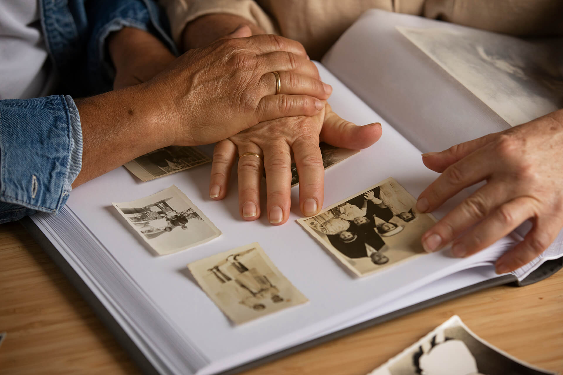 Memory Care Support with Sunshine Home Care Services Senior and family member holding hands over old photographs for memory care