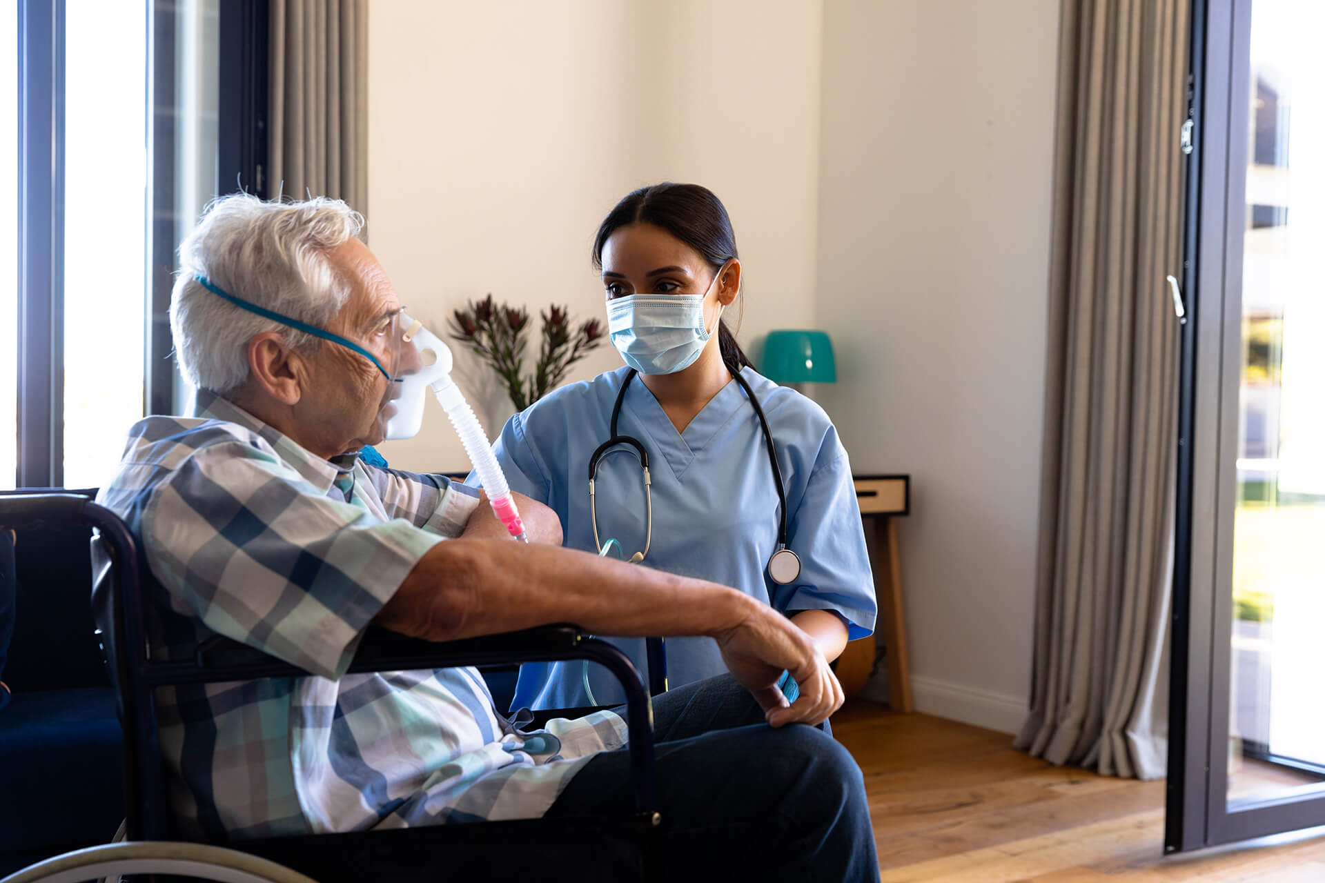 Caregiver assisting senior man with oxygen therapy at home